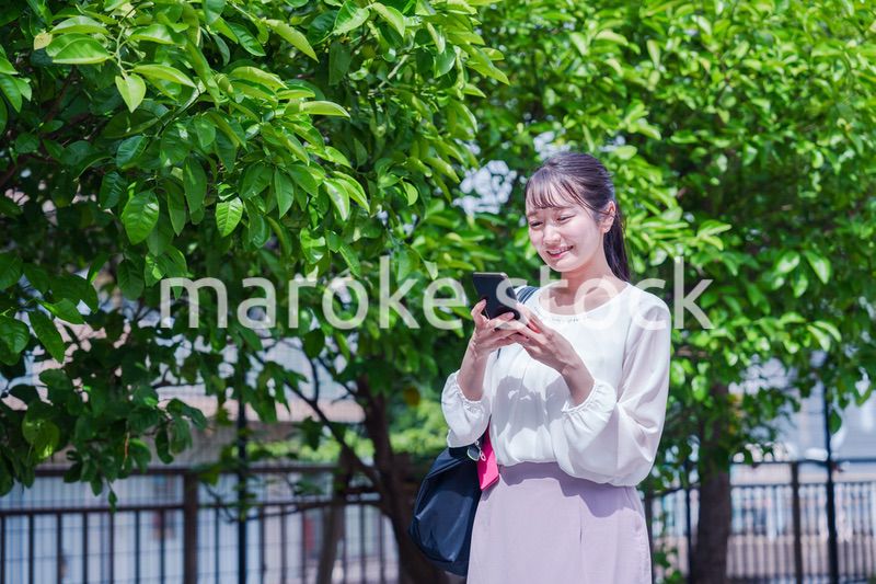 笑顔でスマホを見ながら歩く若い女性