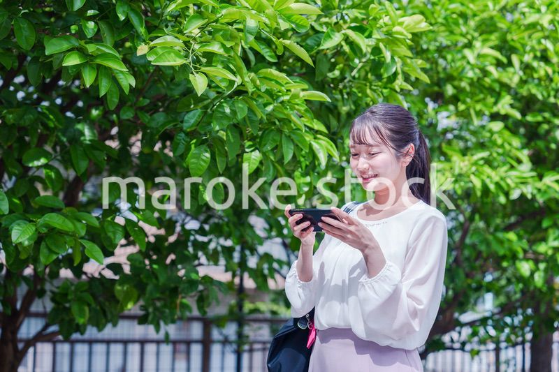 笑顔でスマホを見ながら歩く若い女性