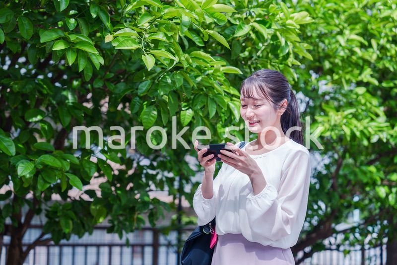 笑顔でスマホを見ながら歩く若い女性