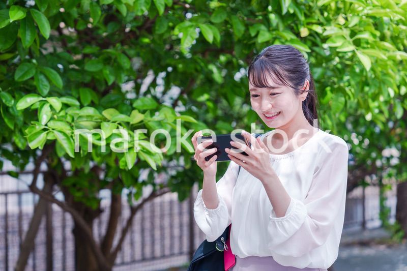 笑顔でスマホを見ながら歩く若い女性