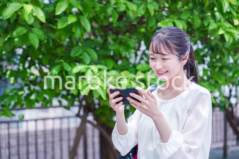 笑顔でスマホを見ながら歩く若い女性