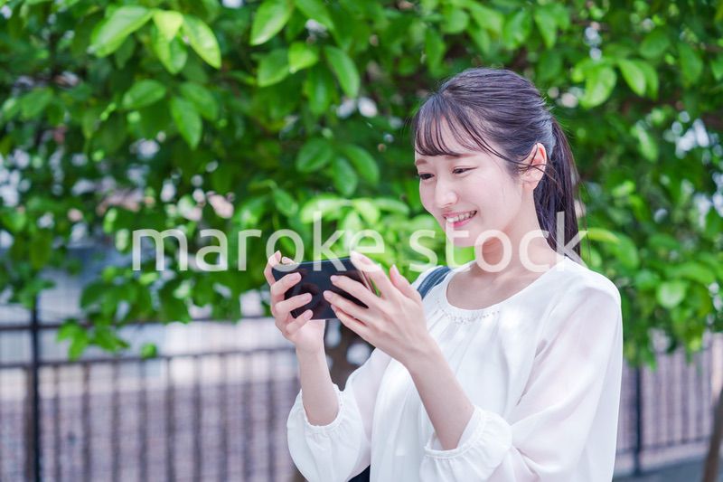 笑顔でスマホを見ながら歩く若い女性