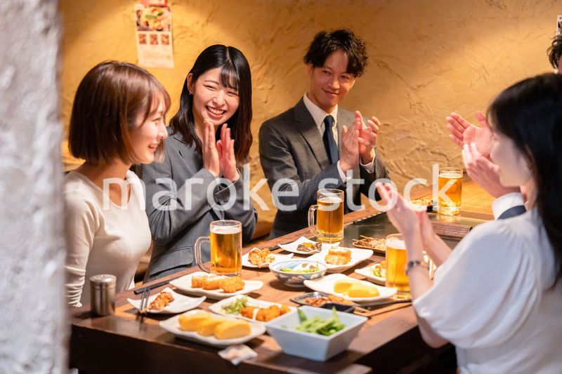居酒屋で拍手をするビジネスパーソン