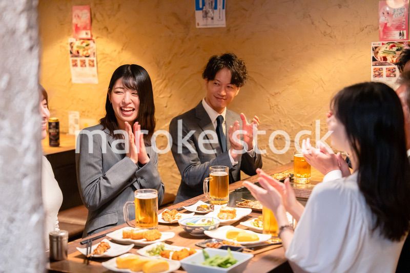 居酒屋で拍手をするビジネスパーソン