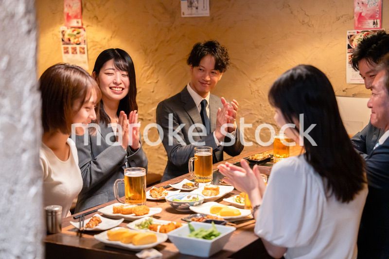 居酒屋で拍手をするビジネスパーソン