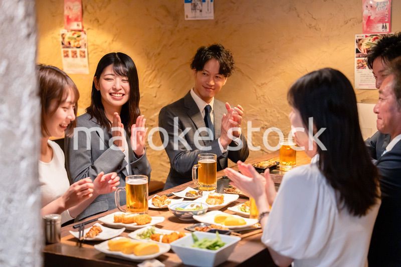 居酒屋で拍手をするビジネスパーソン