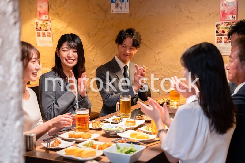 居酒屋で拍手をするビジネスパーソン