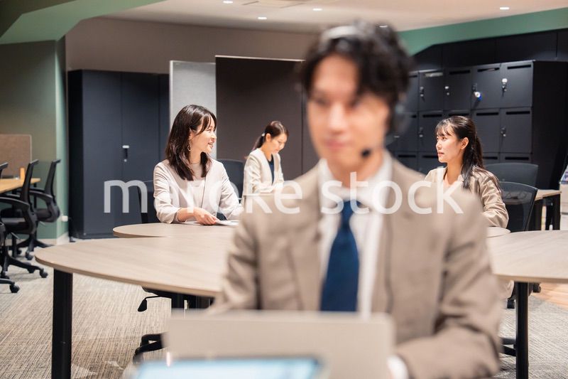 オフィスで楽しく話しながら働く女性