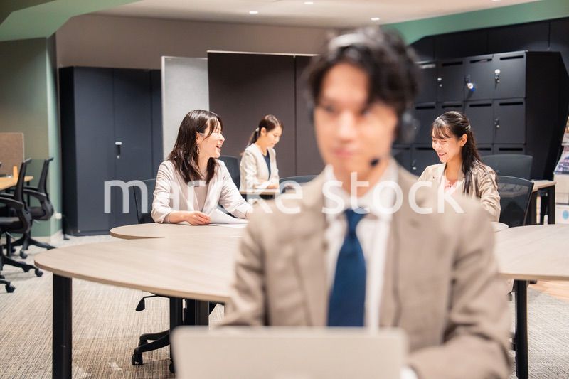 オフィスで楽しく話しながら働く女性