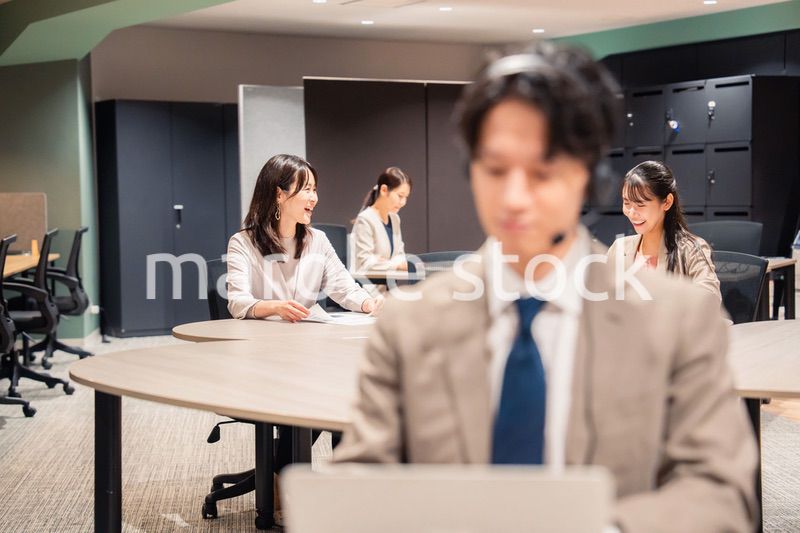 オフィスで楽しく話しながら働く女性