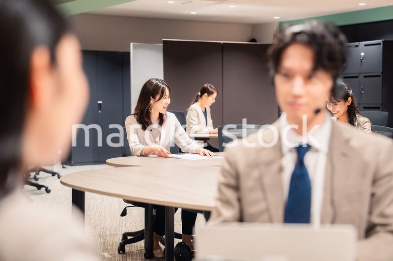 オフィスで楽しく話しながら働く女性