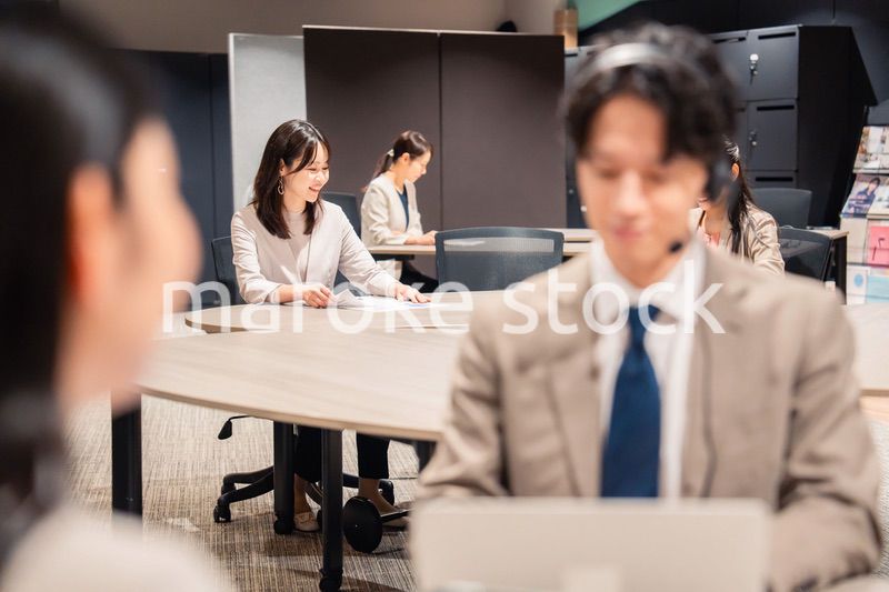 オフィスで楽しく話しながら働く女性