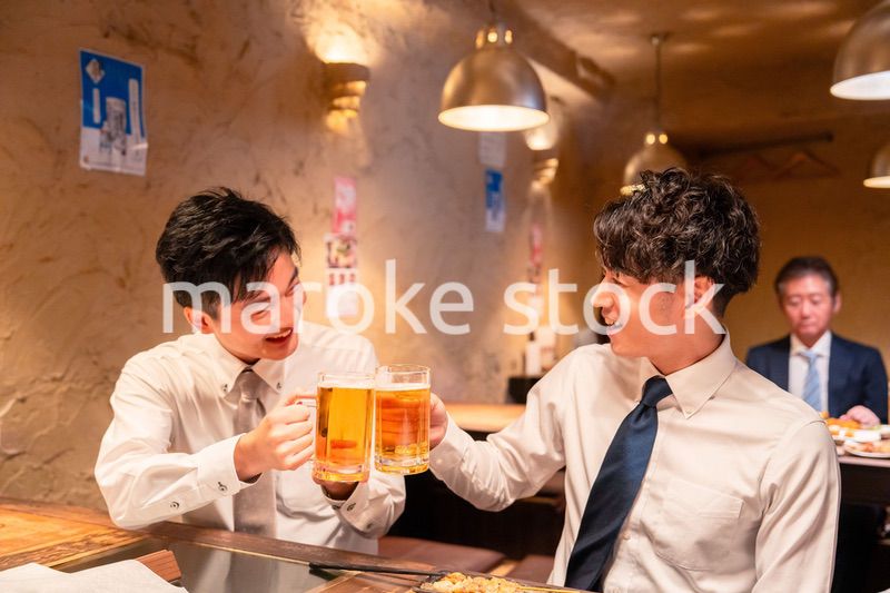 居酒屋でビールを飲む二人の若手ビジネスマン