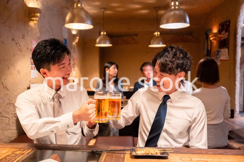 居酒屋でビールを飲む二人の若手ビジネスマン