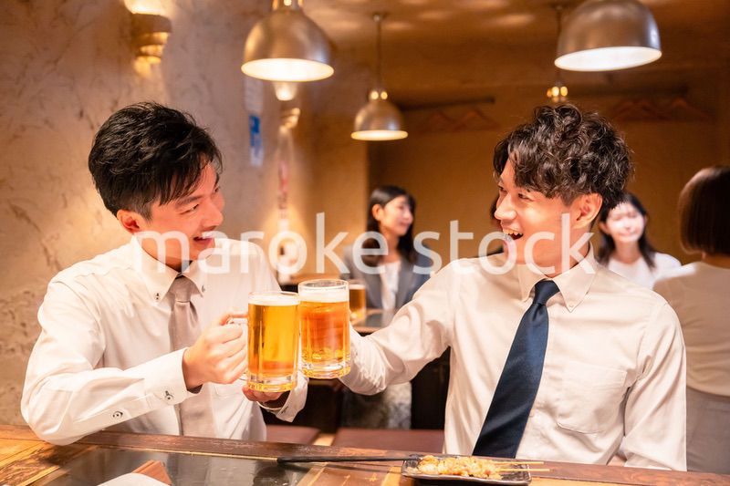居酒屋でビールを飲む二人の若手ビジネスマン