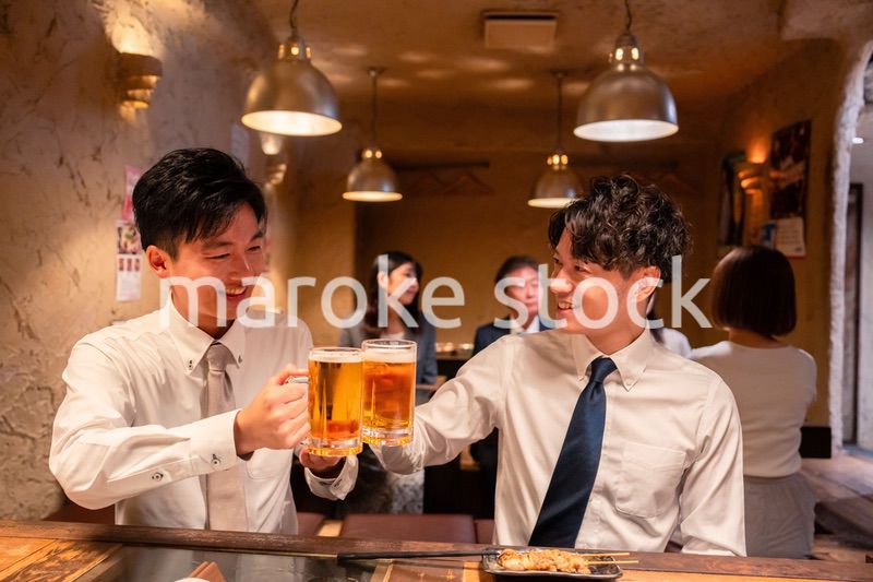 居酒屋でビールを飲む二人の若手ビジネスマン