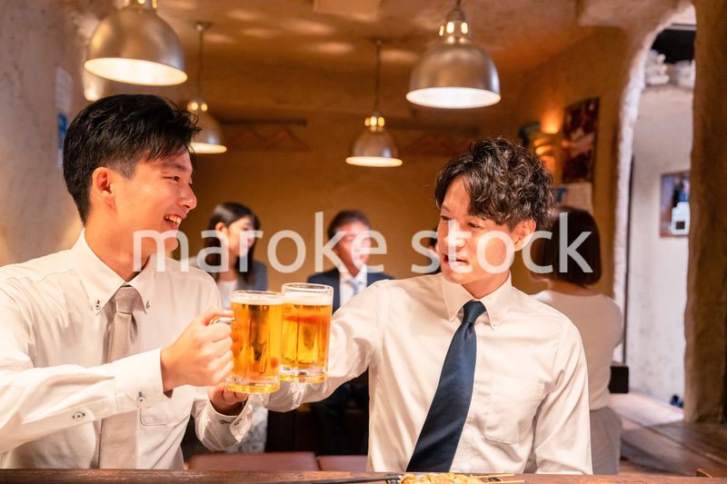 居酒屋でビールを飲む二人の若手ビジネスマン