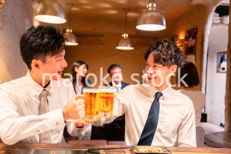 居酒屋でビールを飲む二人の若手ビジネスマン