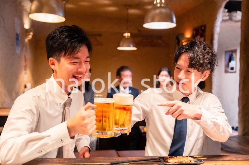 居酒屋でビールを飲む二人の若手ビジネスマン