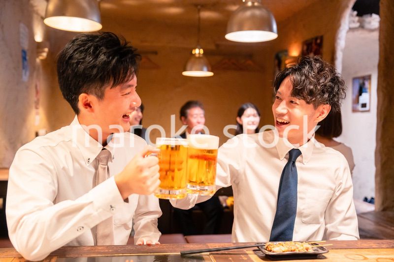居酒屋でビールを飲む二人の若手ビジネスマン