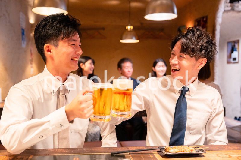居酒屋でビールを飲む二人の若手ビジネスマン