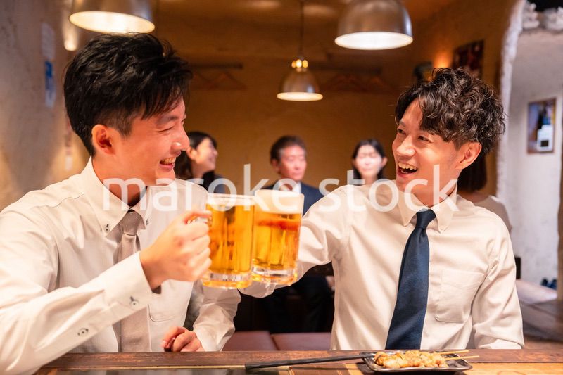 居酒屋でビールを飲む二人の若手ビジネスマン