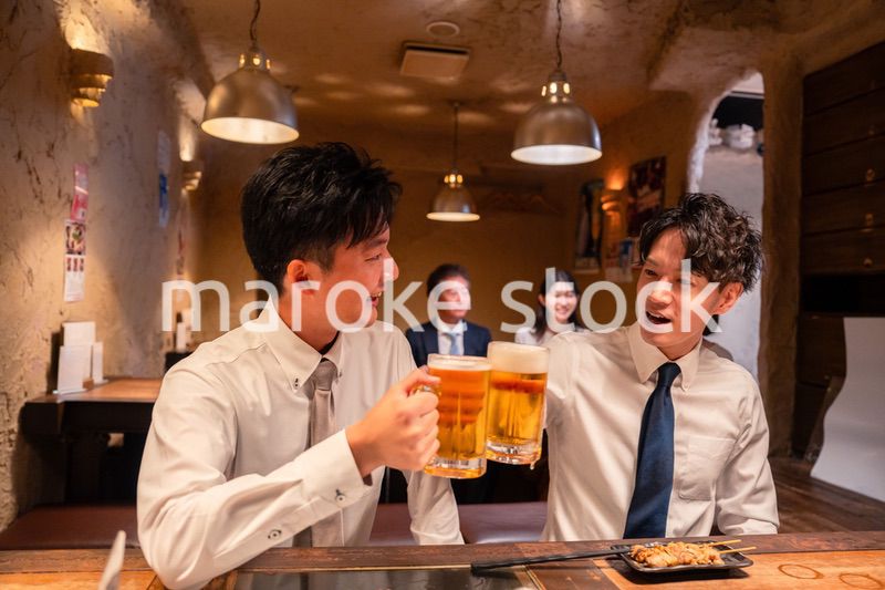 居酒屋でビールを飲む二人の若手ビジネスマン