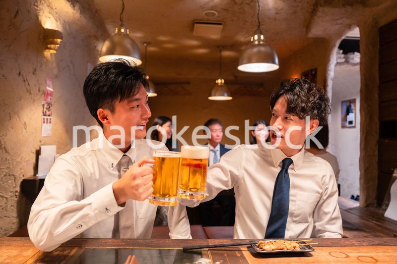 居酒屋でビールを飲む二人の若手ビジネスマン