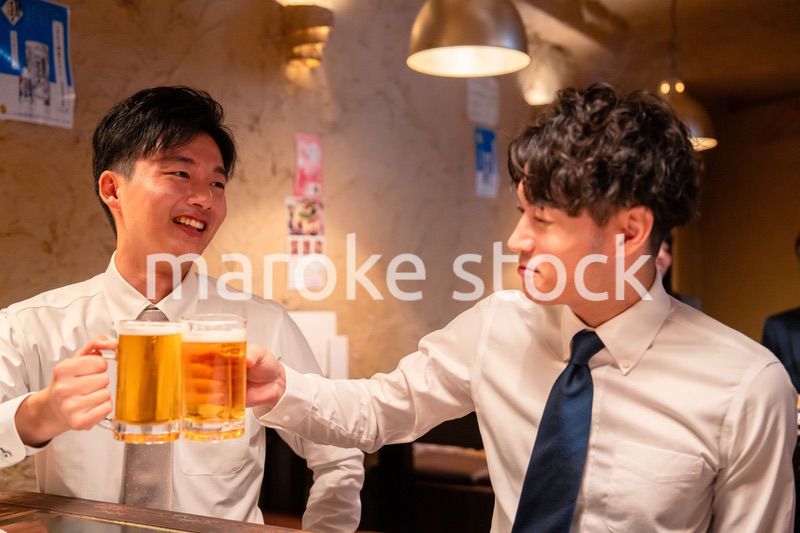 居酒屋でビールを飲む二人の若手ビジネスマン