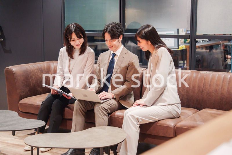 オフィスのソファーでカジュアルに打ち合わせをするビジネスパーソン