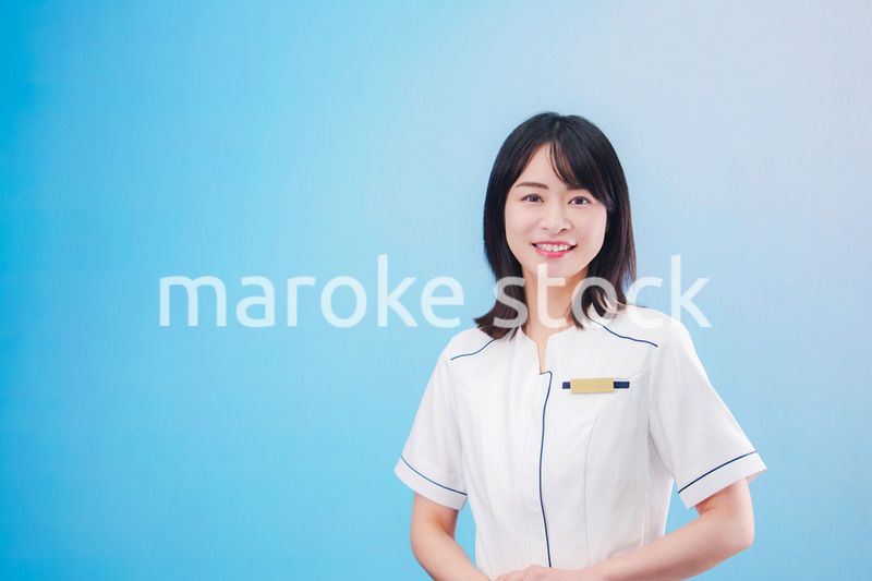 クリニックの受付をする若い女性スタッフ（水色背景）