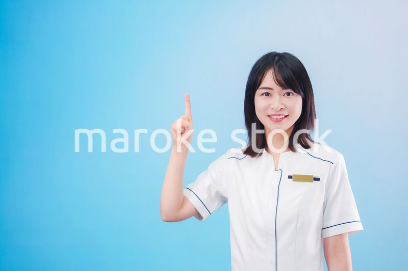 クリニックの受付をする若い女性スタッフ（水色背景）