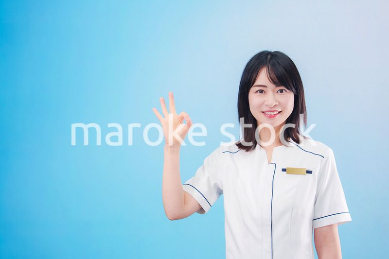 クリニックの受付をする若い女性スタッフ（水色背景）