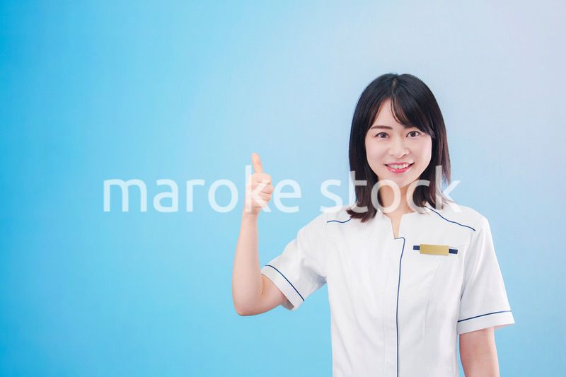 クリニックの受付をする若い女性スタッフ（水色背景）