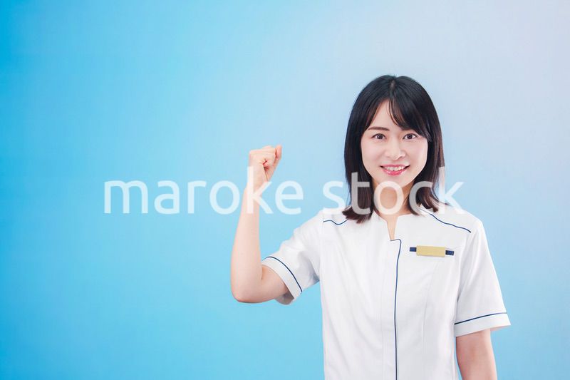 クリニックの受付をする若い女性スタッフ（水色背景）