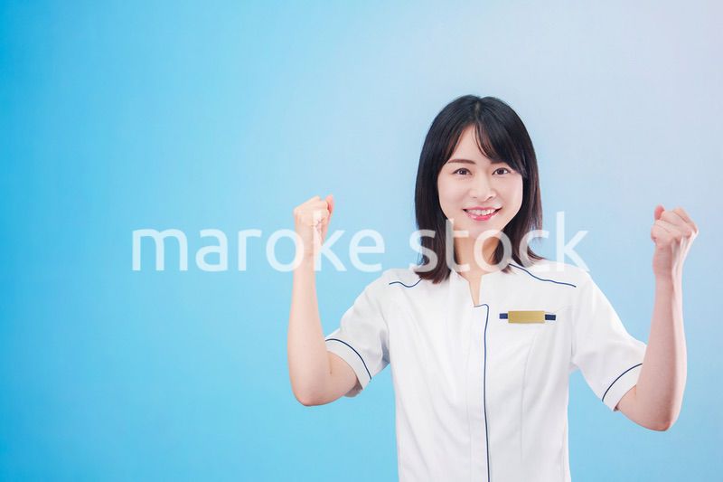 クリニックの受付をする若い女性スタッフ（水色背景）