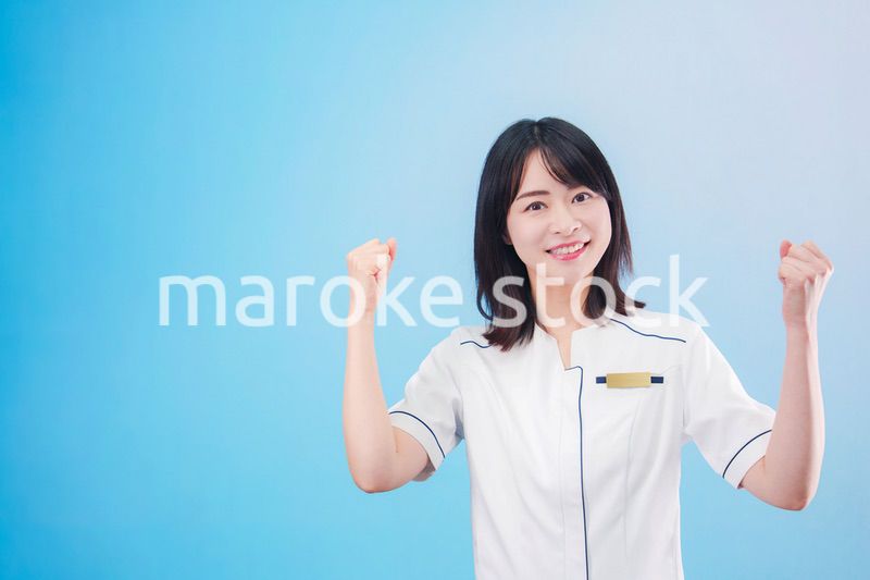 クリニックの受付をする若い女性スタッフ（水色背景）