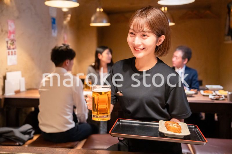 ビールを提供する居酒屋の女性スタッフ