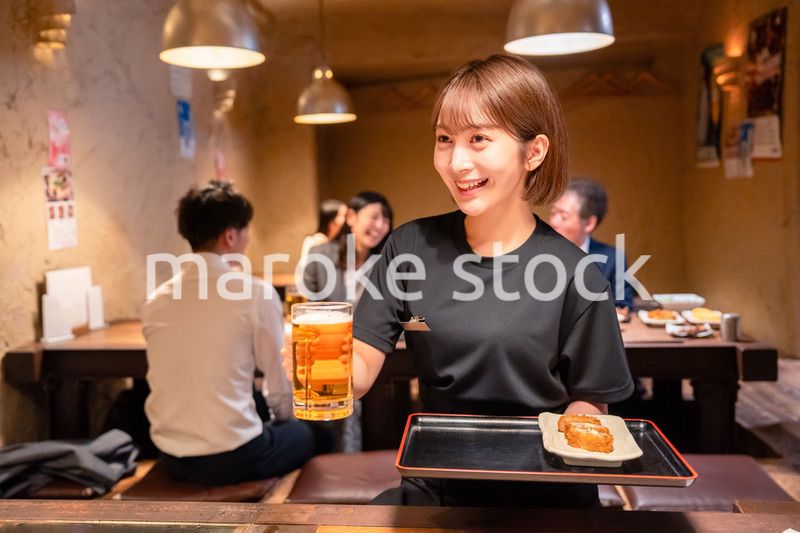 ビールを提供する居酒屋の女性スタッフ