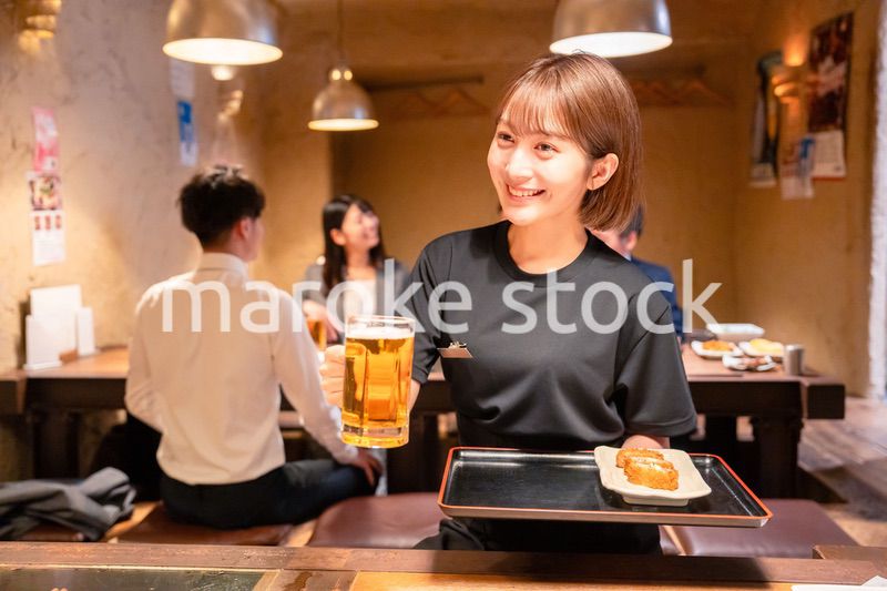 ビールを提供する居酒屋の女性スタッフ