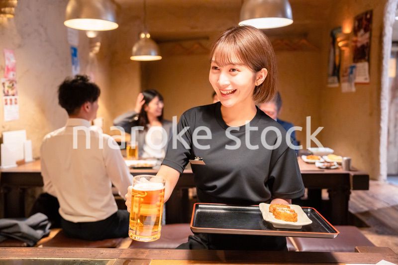 ビールを提供する居酒屋の女性スタッフ