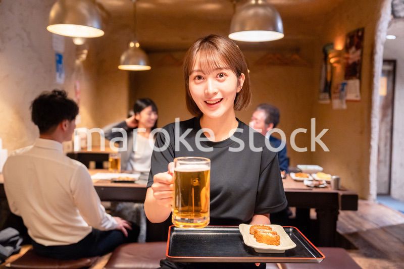 ビールを提供する居酒屋の女性スタッフ