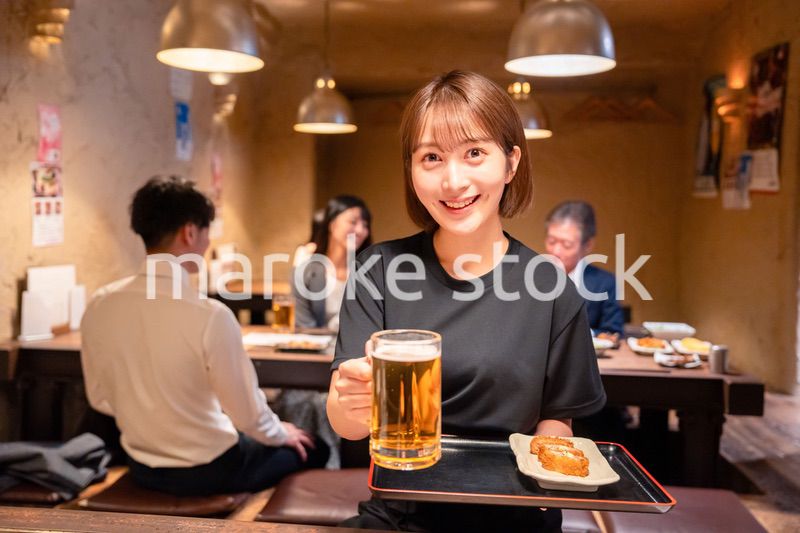 ビールを提供する居酒屋の女性スタッフ