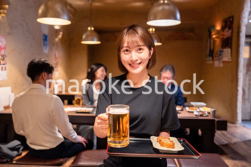 ビールを提供する居酒屋の女性スタッフ
