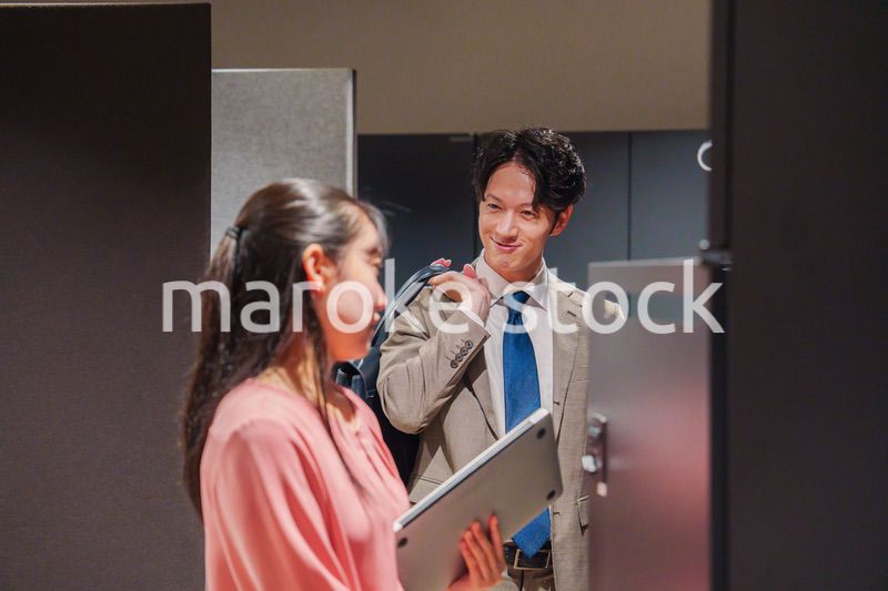 オフィスのロッカーで会話をする男女の会社員