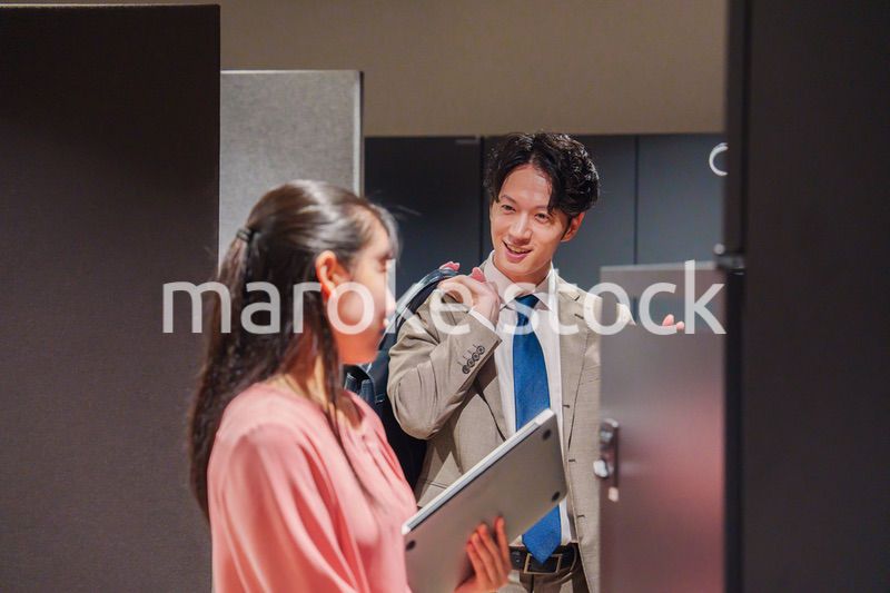 オフィスのロッカーで会話をする男女の会社員