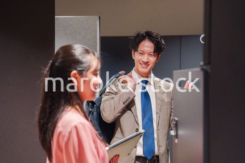 オフィスのロッカーで会話をする男女の会社員