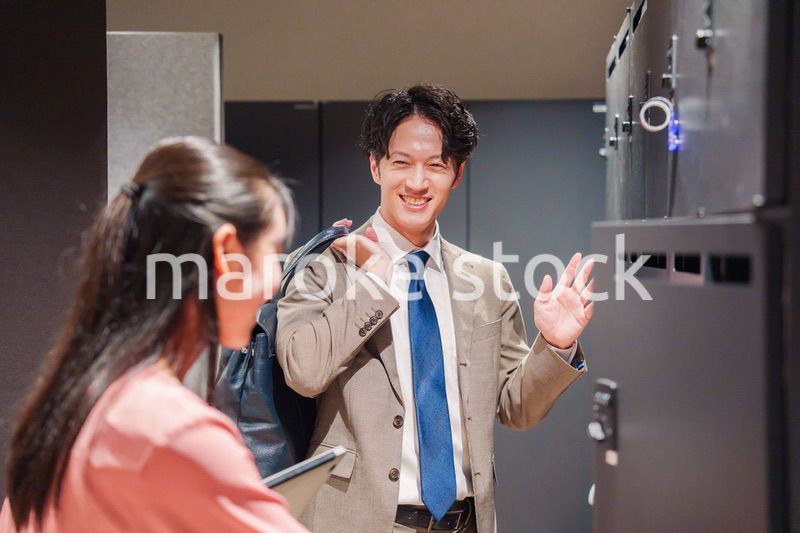 オフィスのロッカーで会話をする男女の会社員