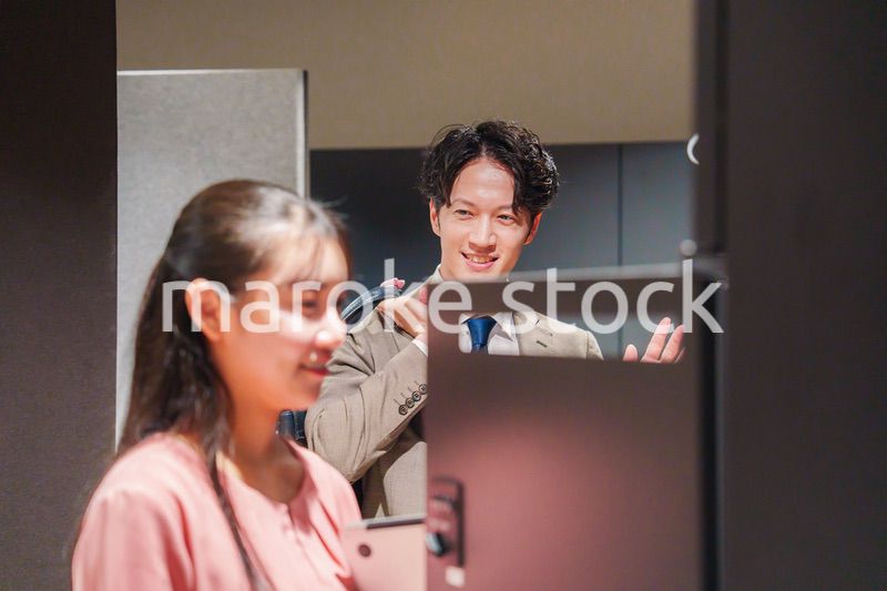 オフィスのロッカーで会話をする男女の会社員