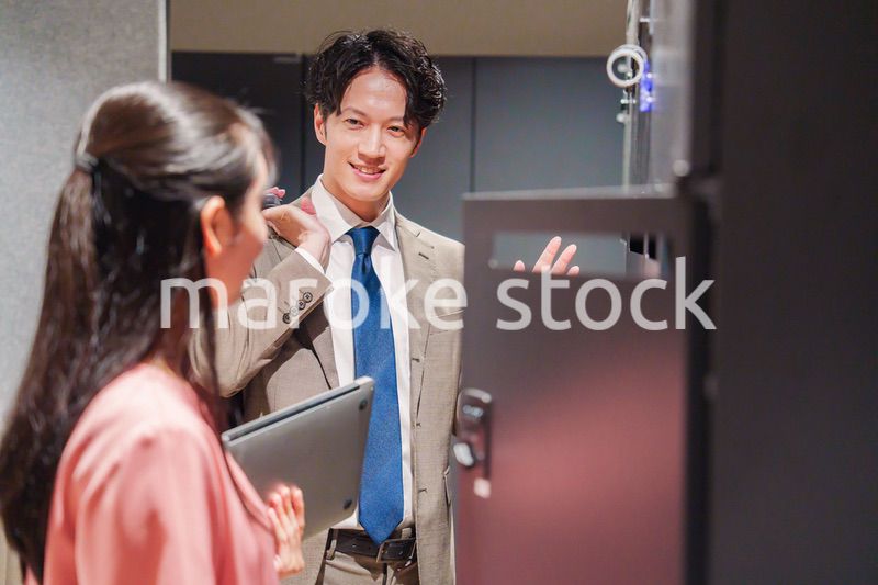 オフィスのロッカーで会話をする男女の会社員